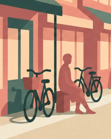 Une silhouette assise entre 2 vélos, devant les vitrines aux tons corail