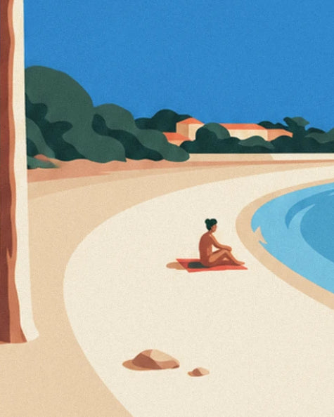 A woman sitting on her red towel in the curve of the pale sandy beach lined with pines