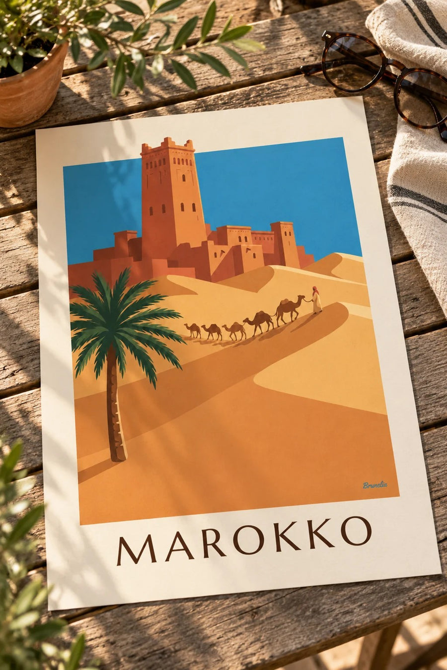 Kasbah ja kamelikaravaani Marokon autiomaassa juliste: pöydällä