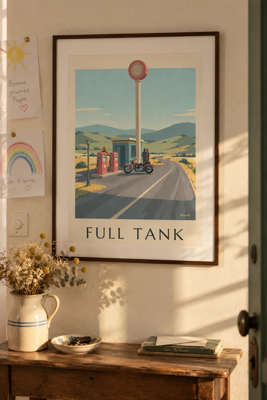 Poster of a classic motorcycle parked in front of a gas station: framed on the wall