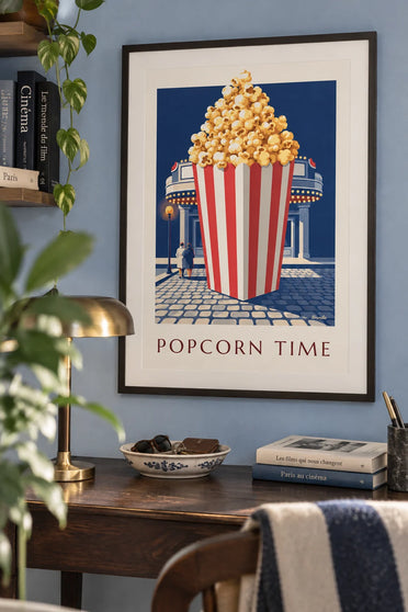 Juliste punavalkoraidallinen kuuma popcorn-ämpäri elokuvateatterin edessä: kehystettynä seinällä